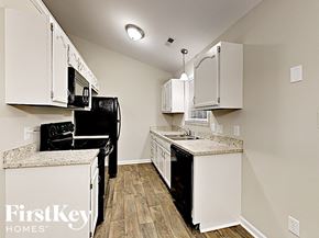 Charlotte house for rent - a kitchen with white cabinets and a black refrigerator