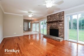 Charleston house for rent - an empty living room with a brick fireplace and wood floors