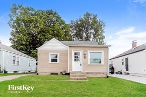 Indianapolis house for rent - A beige house with a white door and a small porch.