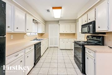 Spring house for rent - A kitchen with black appliances and white cabinets.
