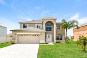 Kissimmee house for rent - a beige house with a garage and a palm tree