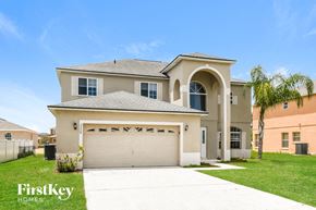 Kissimmee house for rent - a beige house with a garage and a palm tree