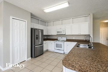 Kissimmee house for rent - a kitchen with white cabinets and a granite counter top