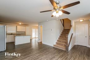 Cumming house for rent - A spacious room with a staircase leading to the upper floor.