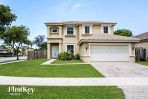 Homestead house for rent - a beige house with a garage and a lawn