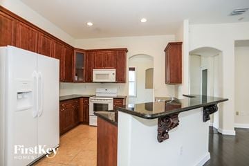 Homestead house for rent - a kitchen with wooden cabinets and white appliances and a counter top