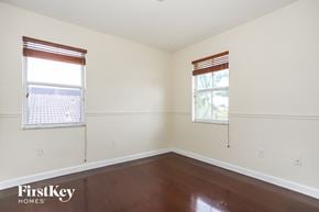 Homestead house for rent - a bedroom with white walls and wood floors and two windows