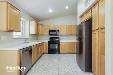 Avondale house for rent - A kitchen with wooden cabinets and a black refrigerator.