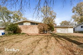 Florissant house for rent - A house with a brown wall and a white garage door is for sale.