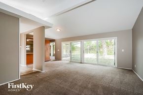 Florissant house for rent - A spacious room with a carpeted floor and a sliding glass door leading to a garden.