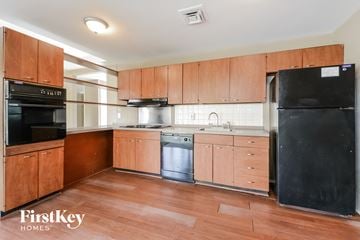 Florissant house for rent - A kitchen with wooden cabinets and a black fridge.