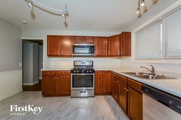 Florissant house for rent - a kitchen with wooden cabinets and stainless steel appliances and a sink