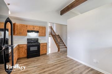 Crest Hill house for rent - a kitchen with wooden cabinets and a black stove and a staircase