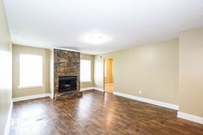 Memphis house for rent - an empty living room with a fireplace and wooden floors