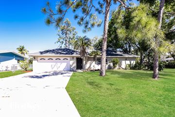Fort Myers house for rent - a white house with a lawn and palm trees