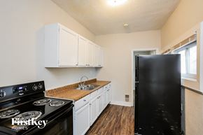 Kansas City house for rent - a kitchen with white cabinets and black appliances and a black refrigerator