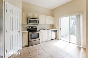Homestead house for rent - a kitchen with white cabinets and appliances and a sliding glass door