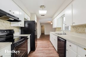 Mount Dora house for rent - a kitchen with white cabinets and black appliances