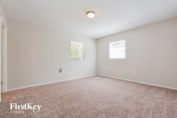 Mount Dora house for rent - a spacious living room with carpet and two windows