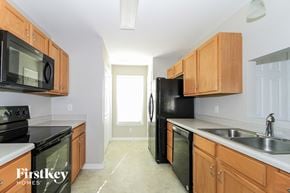 Winston-Salem house for rent - a kitchen with wood cabinets and black appliances and a black refrigerator