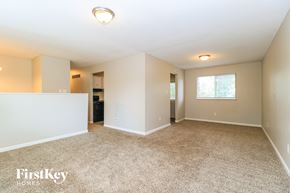 Florissant house for rent - A spacious room with a carpeted floor and a window.