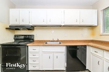 Florissant house for rent - A kitchen with white cabinets and a black stove top oven.