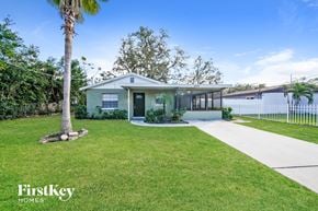 Tampa house for rent - a house with a lawn and a sidewalk and a palm tree