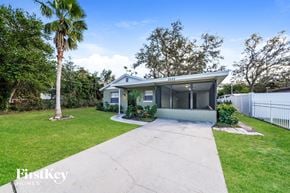 Tampa house for rent - a small blue house with a driveway and a palm tree