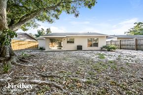 Largo house for rent - A house with a white exterior and a grey roof is surrounded by a gravel area with a tree in the foreground.