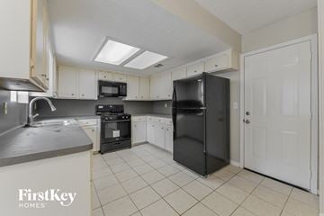 Spring house for rent - a kitchen with white cabinets and a black refrigerator