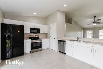 Cape Coral house for rent - a large kitchen with white cabinets and black appliances