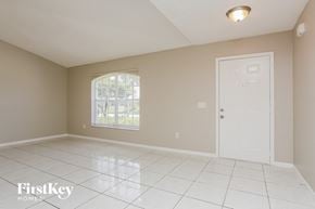 Port St. Lucie house for rent - an empty living room with a white tile floor and a white door