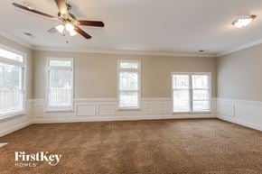 Matthews house for rent - an empty living room with a ceiling fan and three windows