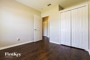 North Port house for rent - a bedroom with white closets and wood flooring and a door to a hallway