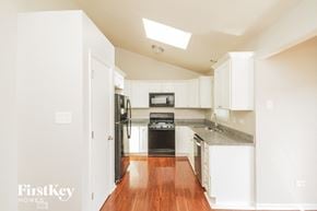 Plainfield house for rent - a kitchen with white cabinets and black appliances and a wood floor