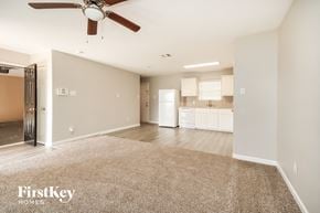 Texas City house for rent - A spacious living room with a carpeted floor and a ceiling fan.