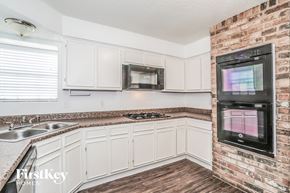 Oak Ridge North house for rent - a kitchen with white cabinets and a brick wall