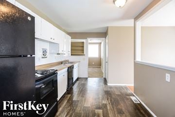 Florissant house for rent - a kitchen with white cabinets and black appliances and wood floors