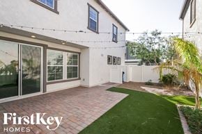 Mesa house for rent - the backyard of a white house with a patio and grass