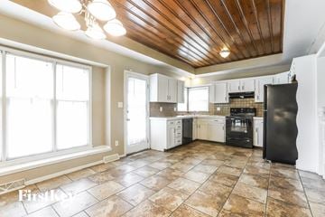 Blue Springs house for rent - a kitchen with white cabinets and tile floors and a black stove
