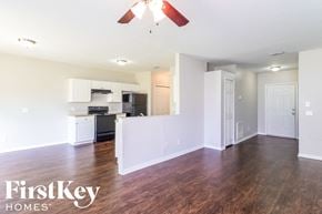 North Port house for rent - an empty living room and kitchen with wood flooring and a ceiling fan
