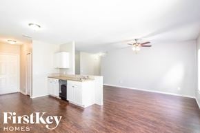 North Port house for rent - an empty living room with a kitchen and a ceiling fan