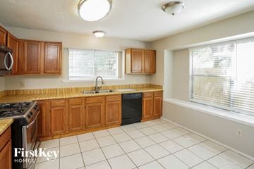 Spring house for rent - a kitchen with wooden cabinets and a sink and a window
