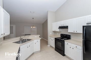 Palm Bay house for rent - A kitchen with white cabinets and black appliances.