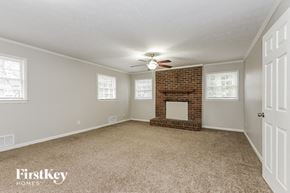 Marietta house for rent - an empty living room with a brick fireplace and a ceiling fan