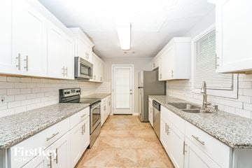 Decatur house for rent - A kitchen with white cabinets and a granite countertop.