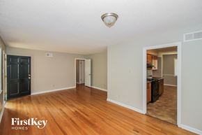 Bartlett house for rent - A spacious room with wooden floors and a sliding door leading to another room.