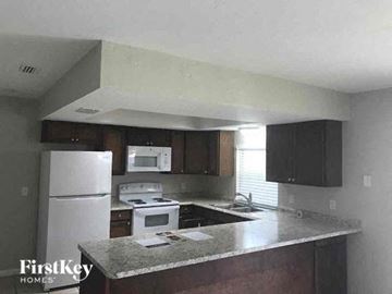 Naples house for rent - A kitchen with a white refrigerator and a granite counter top.
