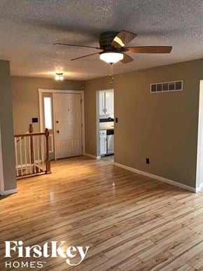 Blue Springs house for rent - an empty living room with a ceiling fan and wood floors