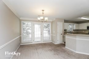 Acworth house for rent - an empty dining room and kitchen with white cabinets and a window
